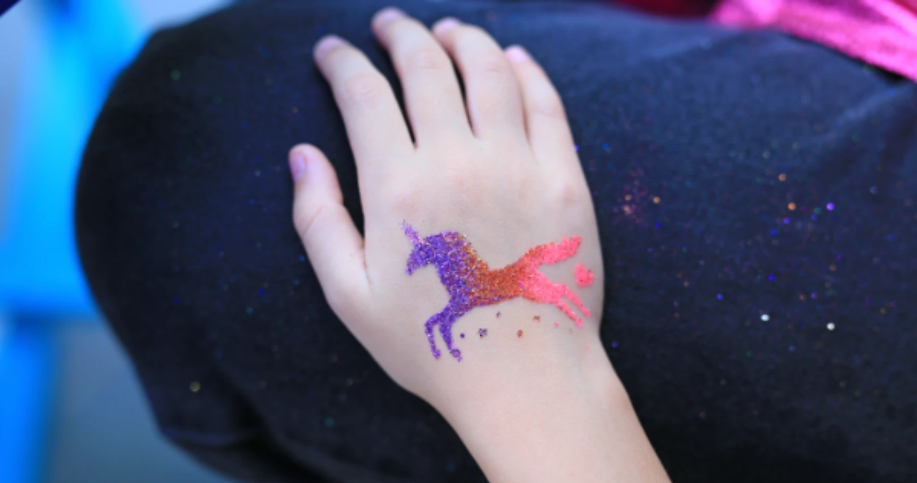 ręka dziecka z brokatowym tatuażem unicorna